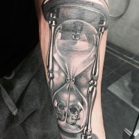 Gran reloj de arena con tatuaje en el antebrazo craneal