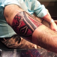 Great red-and-black tribal band tattoo on forearm