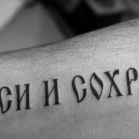 Harsh-lettered russian quote tattoo on arm