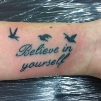 inspira creda in se stesso scritto con uccelli piccoli tatuaggio su polso