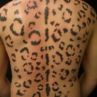 Large black-ink cheetah print tattoo on back