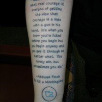 Large printed text quote with blue bird tattoo on arm