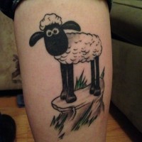 Lovely black-and-white sheep standing on rock tattoo on leg