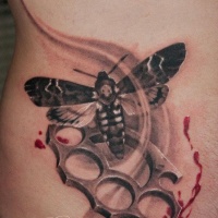 Moth and brass knuckles tattoo on side