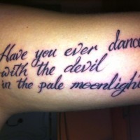 Mystical black-lettered quote tattoo on arm