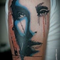 Portrait like colored upper arm tattoo of woman face