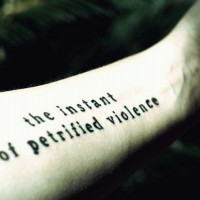 Printed black-and white letters quote tattoo on arm