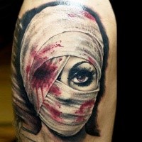 Reali photo like colored upper arm tattoo of bloody woman head with bandage