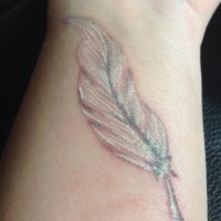 Realistic white-ink feather tattoo on wrist