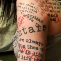 Rotschwarzes Tattoo von chaotisch liegenden Sprüchen am Arm