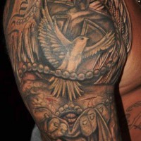 Religious tattoo with dove and cross on upper arm