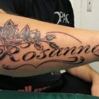 Romantic black-and-white name-quote tattoo with roses tattoo on arm