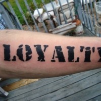 Rough-lettered black loyalty word tattoo on forearm