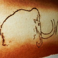 Simple black-contour mammoth figure tattoo on arm