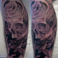Tatuaje de cráneo, polilla y rosa en la pierna