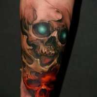 Skull with emerald eyes and red skull tattoo on arm