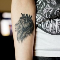 Kleines Tattoo von schwarzweißem König der Löwen in Krone am Unterarm