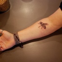 Tattoo von kleiner süßer Biene am Unterarm