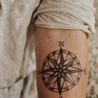 Feines Tattoo von kleinem schwarzweißem Kompass am Unterarm