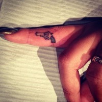 Kleine einfache Pistole Tattoo am Fingerseite