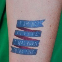 Strong quote on blue ribbon tattoo on arm