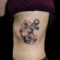 Tender black-and-white anchor in lilies tattoo on rib-side