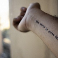 The world is quite here quote tattoo on arm