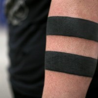 Thick-line black band tattoo on forearm