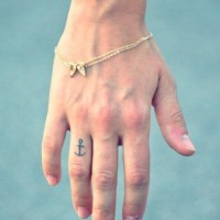 Thin-lined black anchor tattoo on ring finger