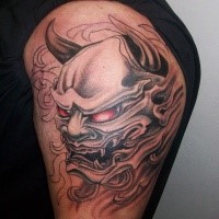 Unfinished Asian style upper arm tattoo of monster mask with red eyes