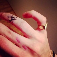 Unusual small black spider tattoo on finger