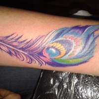 Tatuaje en el antebrazo,
pluma de pavo real de color púrpura