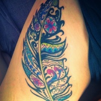 Vivid-colored tribal feather tattoo on thigh