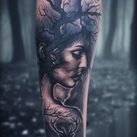 Cabeza de mujer y tatuaje de árbol seco en la muñeca