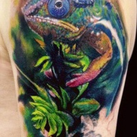 Wonderful colored chameleon sitting on tree branch tattoo on upper arm