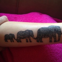 Wonderful great-ornamented elephant family hanging by tales tattoo on arm