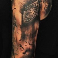 Tatuaje en el brazo, reloj viejo  de la torre estupendo y montón de aves
