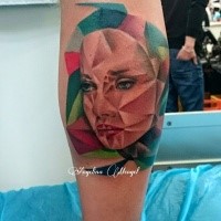 Abstract style colored leg tattoo of unusual looking woman face