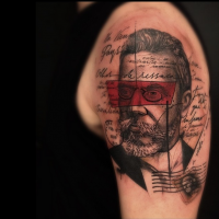 Abstract style colored shoulder tattoo of man portrait with lettering