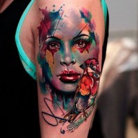 Abstract style colored woman portrait tattoo on shoulder combined with little bird