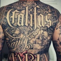 Accurate looking black and white tribal themed tattoo on whole back with lettering