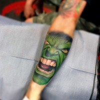 Akkurat aussehendes farbiges Unterarm Tattoo von großem grünem Hulks Kopf
