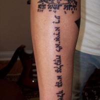 Tatuaje en el antebrazo,
texto en hebreo vertical y corona