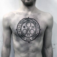 Ancient style black ink chest tattoo of circle shaped ornament with lettering and symbols