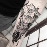 Animal horned skull with flowers forearm length dark colored tattoo in engraving style