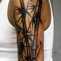Asian bamboo tree detailed dark colored tattoo on upper arm