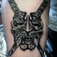 Tatuaje en el antebrazo, máscara asiática con dos espadas cruzadas