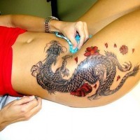 Asian style colored very detailed dragon with flowers tattoo on thigh