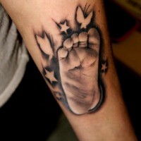 realistico piede di bambino con farfalle e stelle tatuaggio su braccio