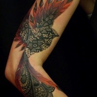 Tatuaje en el brazo, ave imaginado negro con plumas rojas